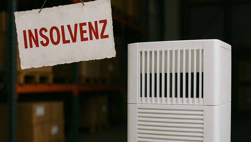 Ein weißer Luftreiniger steht in einem Lagerraum mit gestapelten Kartons auf Metallregalen. Daneben hängt ein Schild mit der Aufschrift ‚INSOLVENZ‘ in roten Buchstaben. Die Szene wirkt nüchtern und symbolisiert die wirtschaftliche Notlage des Unternehmens