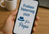 Eine Person hält ein Smartphone in der Hand, auf dessen Bildschirm eine digitale Vatertagsgrußbotschaft für das Jahr 2025 angezeigt wird. Im Hintergrund stehen eine Tasse Kaffee und ein aufgeklappter Laptop auf einem Holztisch, die Szene wirkt ruhig und herzlich
