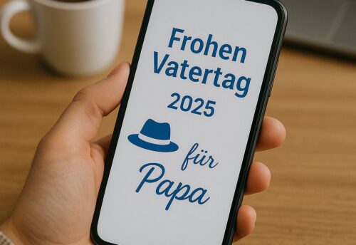 Eine Person hält ein Smartphone in der Hand, auf dessen Bildschirm eine digitale Vatertagsgrußbotschaft für das Jahr 2025 angezeigt wird. Im Hintergrund stehen eine Tasse Kaffee und ein aufgeklappter Laptop auf einem Holztisch, die Szene wirkt ruhig und herzlich