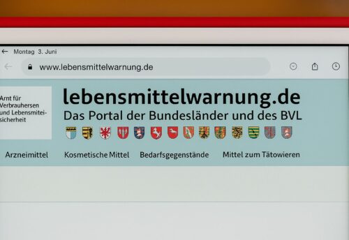 Ein Bildschirm zeigt die Website lebensmittelwarnung.de, das offizielle Portal der Bundesländer und des BVL für Rückrufe und Verbraucherwarnungen. Oben sind die Wappen der Bundesländer zu sehen, darunter Kategorien wie Arzneimittel und Lebensmittel.