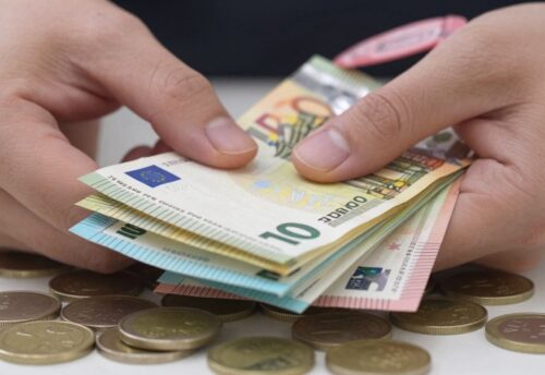 Hand hält Euro-Scheine und Münzen, Bargeld wird gehalten.