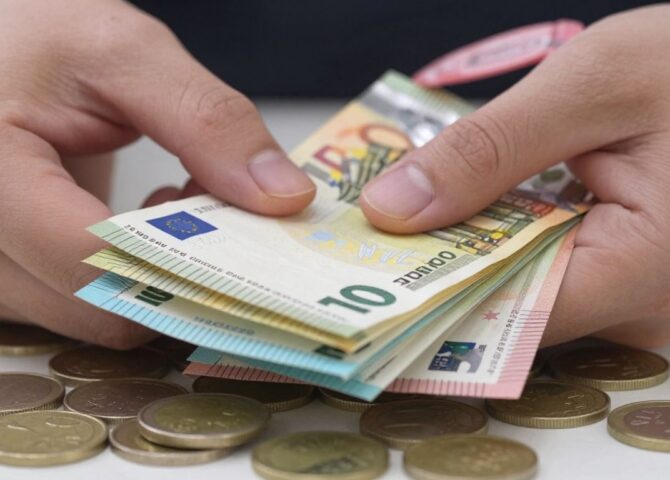 Hand hält Euro-Scheine und Münzen, Bargeld wird gehalten.