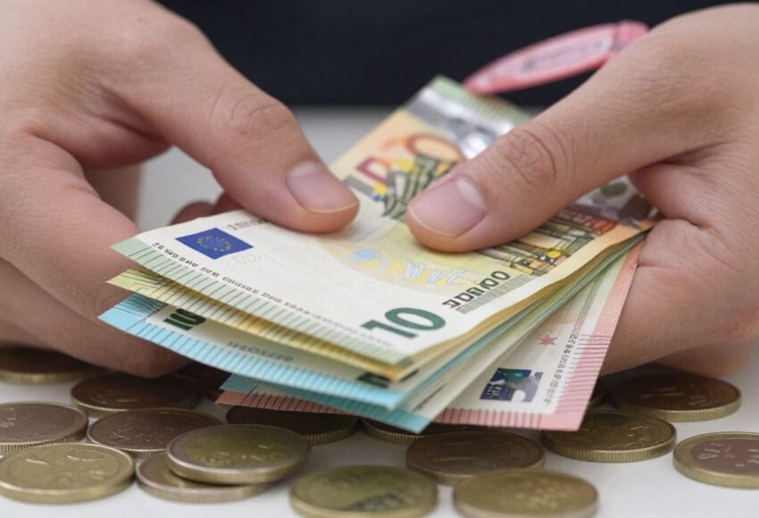 Hand hält Euro-Scheine und Münzen, Bargeld wird gehalten.