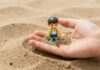 Kind spielt mit Sand und Spielfiguren